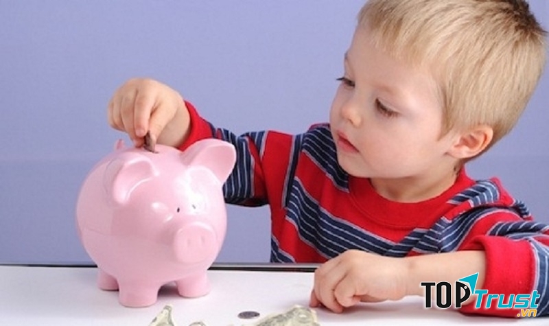 Bé bỏ tiền tiết kiệm vào lợn đất.