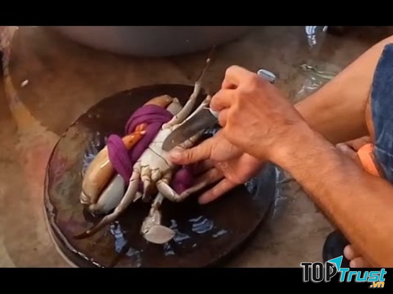 bạn hãy giữ nguyên dây trói, lấy một con dao nhọn, cắm thẳng vào miệng cua và xoay một cái. Cua sẽ chết ngay lập tức và khi luộc sẽ không bị rụng càng