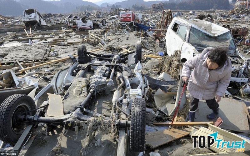 Một phụ nữ tìm chồng đang mất tích nhìn dưới chiếc xe tải bị lật. Ảnh: Reuters.