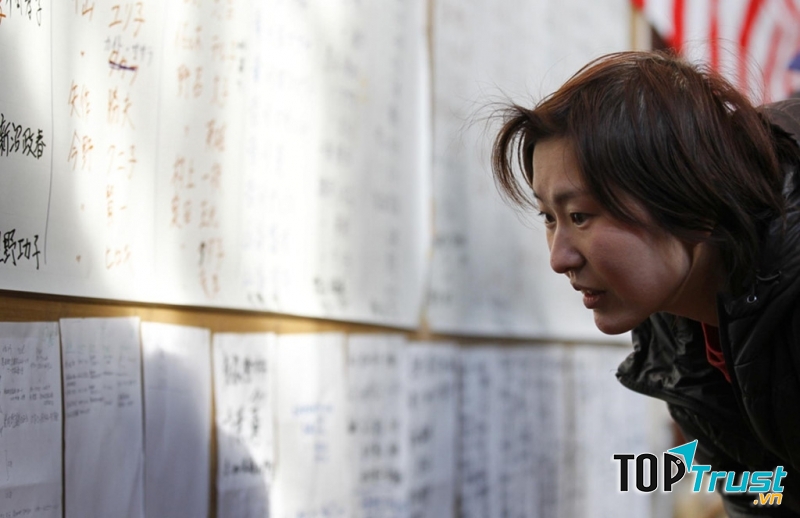 Một người đang tìm danh sách những người sống sót ở một trung tâm sơ tán ở tỉnh Iwate. Ảnh: Reuters.